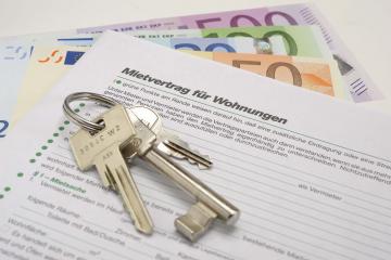 Schlüssel auf einem Mietvertrag und Geldscheinen